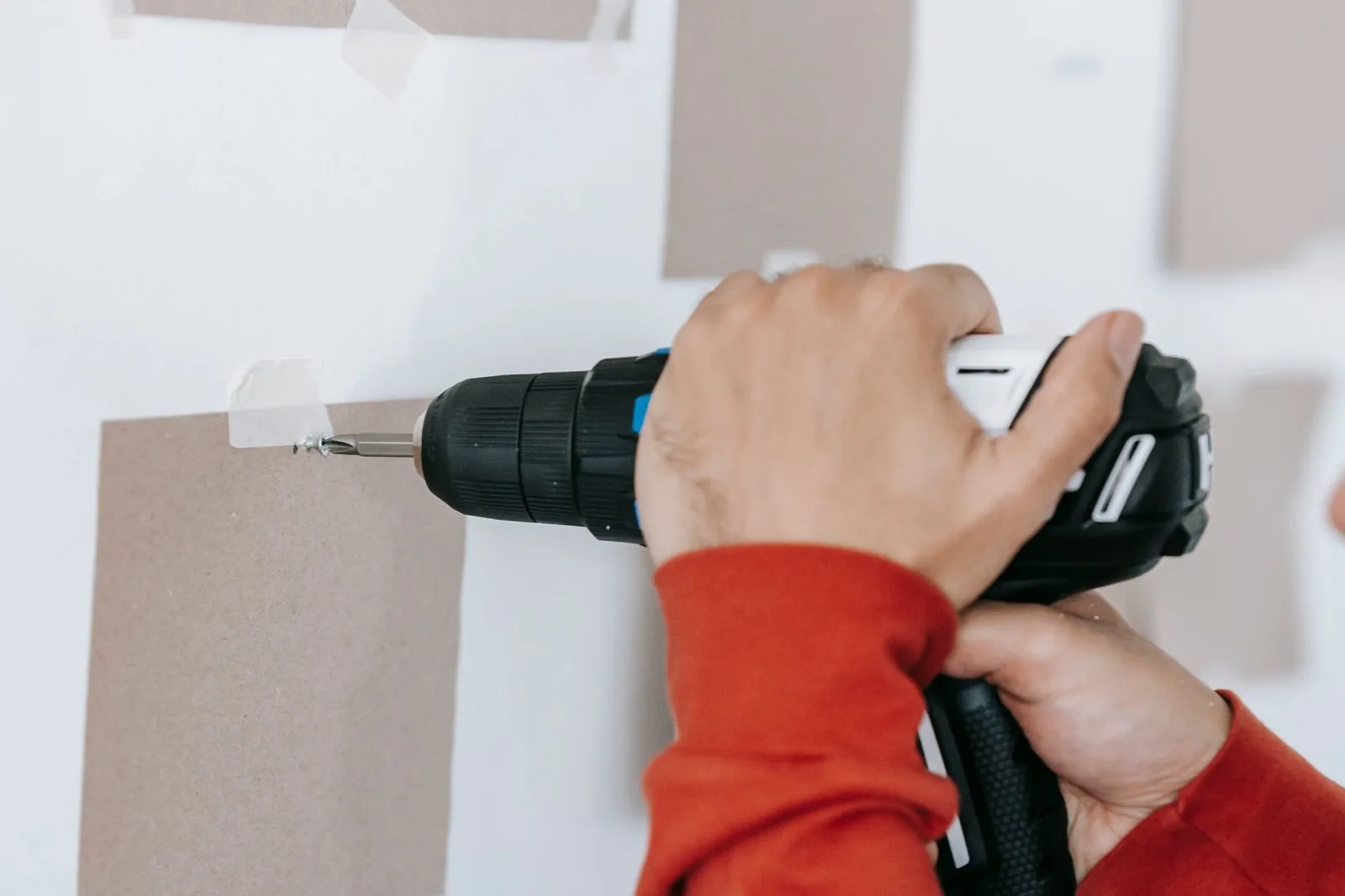 Drilling into a white wall through a paper template taped in place