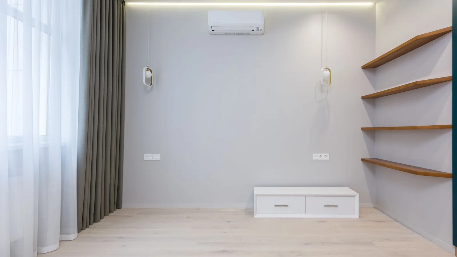 Mini split indoor unit mounted high and centered on a bare wall in an empty room