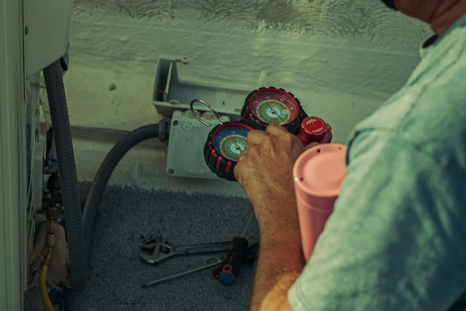 Technician reading a manifold gauge set connected to an outdoor unit