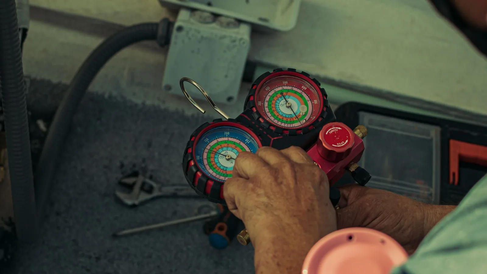 Technician with manifold gauges works near a gray mini split outdoor unit, avoiding common mini split installation errors