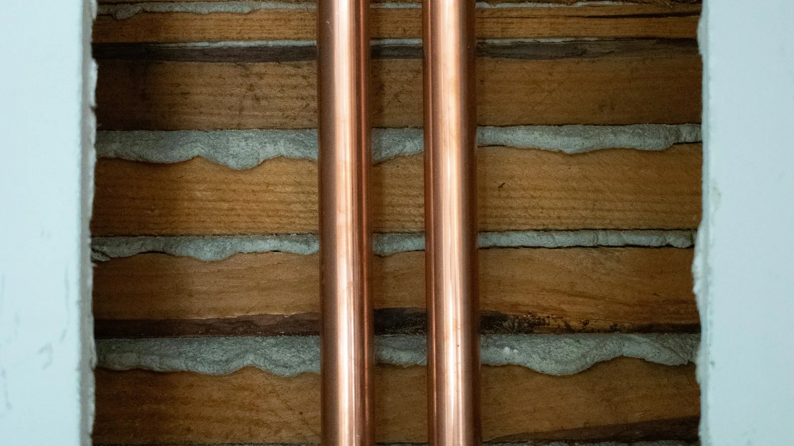 Copper pipes in a wall cavity show mini split line set crawl space routing through exposed lath